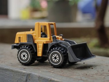 Sarı tekerlek yükleyicisinin yan görüntüsü ya da arka planı bulanık buldozer oyuncağı. inşaat imajı kavramı.