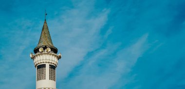 Cami minaresi, hoparlörlü müslüman namazı için ya da açık mavi gökyüzüne karşı açık mavi bulutlu bir canavar.