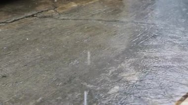Beton zemine düşen yağmur damlaları ve kenarlarında akan görünür yağmur damlaları. Kış mevsiminde yağmurlu bir atmosfer. Endonezya 'da tropikal iklim.