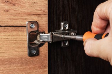 Oda dolabının kapı menteşesini ayarlıyorum.