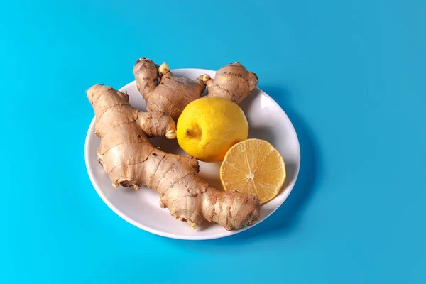 A source of vitamins. Ginger and lemon on a white plate