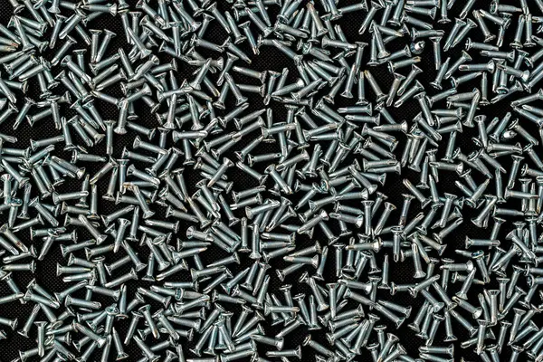 Siyah arkaplanda metal kendini tıklatan vidalar