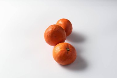 Olgun mandalinalar beyaz bir zemin üzerine serilmiş doğal C vitamini kaynağı