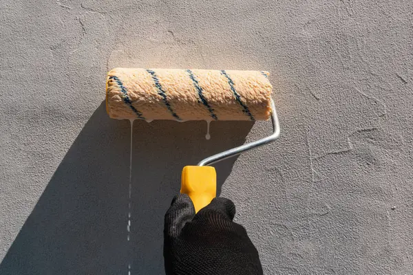 Duvar kaplaması. Duvarda bir silindir ile astar uygulamak