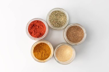 Cam kavanozdaki baharat tozu, beyaz arka planda izole edilmiş.