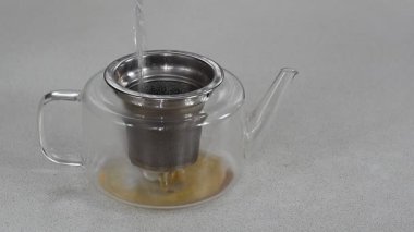 Buharda pişen sıcak siyah çayın yakın plan resmi çaydanlıktan şeffaf bir bardağa yavaşça dökülüyor..