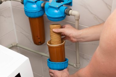 Ev filtreleme sistemindeki su arıtma filtresi değiştiriliyor.