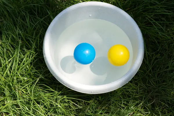 Çocuk plastik toplarla suda oynuyor..