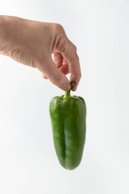 Beyaz bir arka planda yeşil dolmalık biber. Elinde Bulgar biberi tutan adam.