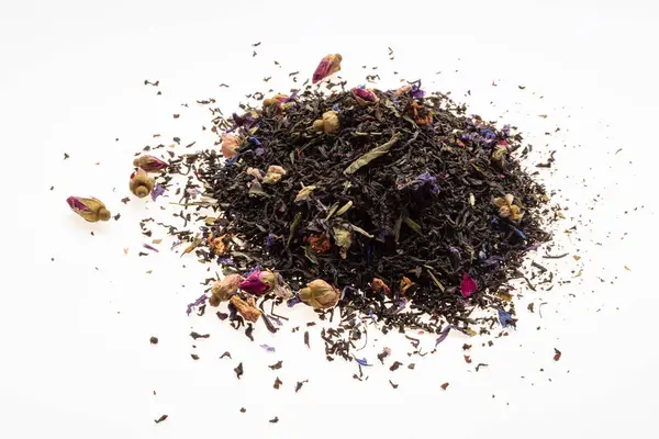Ceylon tea with dried flower petals. A pile of black dry tea leaves on a white background