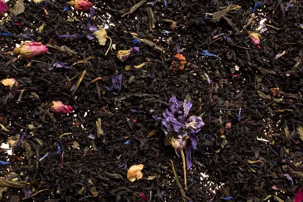 Black Ceylon tea with dried flowers. A background of loose black tea with dried flower petals