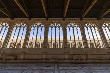 Süslü çizgili Gotik kemerler İtalya 'nın Pisa kentindeki Camposanto Anıtı Manastırı. Tonozlu tavan koyu ahşap kirişler içeriyor, açık renkli taş duvarlarla çelişiyor..