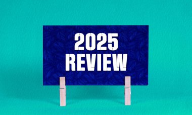 2025 REViEW Sembolü. Koyu Mavi Dikdörtgen Kağıt üzerinde 2025 sayılı kavramsal sözcükler. Ahşap Clothespin Yeşil Arkaplan tarafından tutuluyor. İş 2025 Yeniden İzleme Uzayı Kopyalama Konsepti