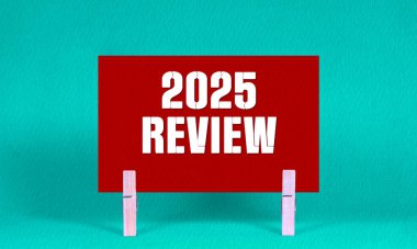 2025 REViEW Sembolü. Sözcükler 2025 Kırmızı Dikdörtgen Kağıt üzerinde Tahta Clothespin Yeşil Arkaplan tarafından tutulan. İş 2025 Yeniden İzleme Uzayı Kopyalama Konsepti