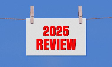 2025 REViEW Sembolü. Sözcükler 2025 Beyaz Dikdörtgen Kağıt üzerinde ahşap bir mandalda asılı mavi arka plan. İş 2025 Yeniden İzleme Uzayı Kopyalama Konsepti
