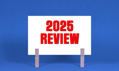 2025 REViEW Sembolü. Sözcükler 2025 Beyaz Dikdörtgen Kağıt üzerinde Tahta Çamaşır Mandalı Mavi Arkaplan. İş 2025 Yeniden İzleme Uzayı Kopyalama Konsepti