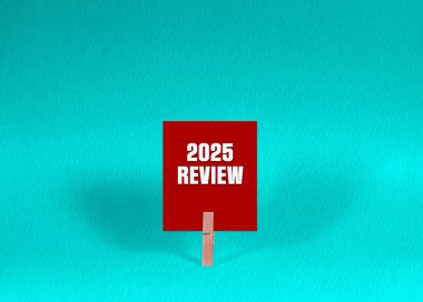 2025 REVIEW Symbol. Concept words 2025 REVIEW on Red Square Paper Held by Wooden Clothespin Green Background. Business 2025 REVIEW Concept with Copy Space clipart