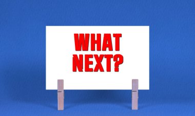 Ne Sonraki Sembol. Sözcükler Beyaz Dikdörtgen Kağıt 'ta Sırada Ne Var? Ahşap Mandal Mavi Arkaplan. Kopyalama Alanı ile Sonraki Konsept