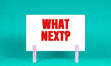 Ne Sonraki Sembol. Sözcükler Beyaz Dikdörtgen Kağıt 'ta sırada ne var? Ahşap Mandallı Yeşil Arkaplan. Kopyalama Alanı ile Sonraki Konsept