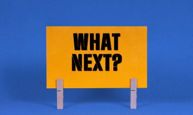 Ne Sonraki Sembol. Sözcükler Sarı Dikdörtgen Kağıt 'ta Sırada Ne Var Tahta Elbise Mandalı Mavi Arkaplan. Kopyalama Alanı ile Sonraki Konsept