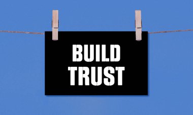 Build Trust Symbol. Concept words Build Trust on Black Rectangle Paper Hanging on a Wooden Clothespin Blue Background. Business Build Trust Concept with Copy Space clipart