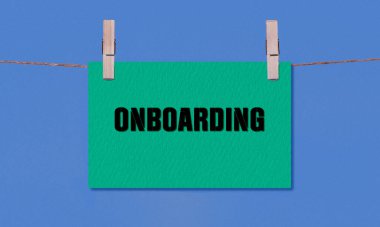 Onboard Sembolü. Tahta bir mandalda asılı yeşil dikdörtgen kağıdın üzerinde mavi arka planda bulunan kavramsal kelimeler. Kopyalama Alanı ile İş Sürdürme Kavramı