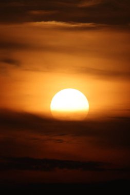 Hollanda 'da gökyüzünde sıcak altın ve kehribar tonları bırakan, dramatik bulutların ardında parlayan bir güneş batar.