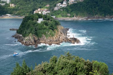 Bilbao 'nun merkezinde güzel bir ağaç ve ferahlatıcı bir gölgesi olan açık hava manzaralı bir parkta, sağda kübik, modern bir metal geometrik heykel var.