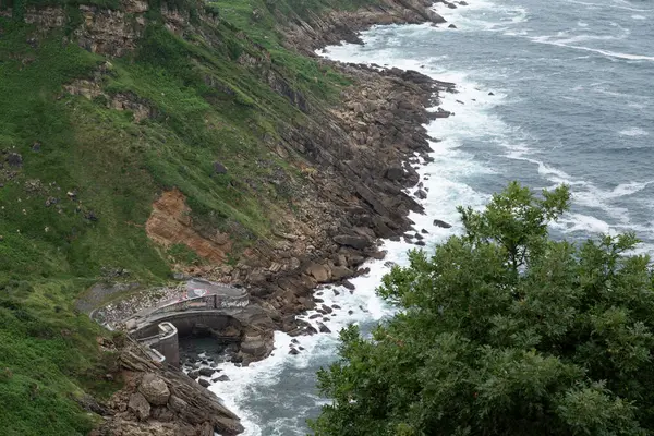 Dalgaların kayalara çarpıp kırıldığı engebeli kıyı şeridi manzarası. Bir köprü görüyoruz. Fotoğraf İspanya 'daki Donostia San Sebastian' daki Igueldo Dağı 'ndan çekildi..