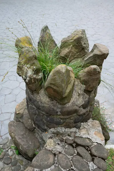 stock image At the station on top of the mount Artxanda funicular in Bilbao you can see this strange vase made of rocks, at the foot of a staircase: grass is growing inside.