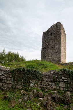 The tower of the medieval castle of Solimbergo, fraction of Sequals in Friuli. These ruins are at the top of a hill, we are in autumn. We see a wooden staircase with its ledge and over us a dramatic cloudy sky. clipart