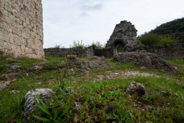 Kuzey İtalya 'daki Solimbergo Ortaçağ Şatosu' nun (FVG bölgesi) kayalık girişi, arka plandaki ve sol taraftaki kale duvarları. Bu kalıntılar bir tepenin üstünde, kısa bir yürüyüşten sonra ulaşılabilir. Gökyüzü bulutlu ve dramatik.