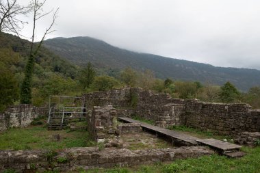 İtalya 'nın Friuli bölgesindeki Meduno antik şatosunun harabelerinde taş duvar. Yenileme aşamasında. Ürkütücü, ürkütücü ve terk edilmiş. Tahta kaldırımlı metal bir iskele var. Gün sisli..