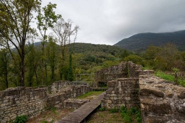 İtalya 'nın Friuli Venezia Giulia bölgesindeki Meduno antik kalesinin kalıntıları. Yenileme aşamasında. Uzun tahta bir iskele, metal bir yapı iskelesi ve tarihi bilgilerle dolu bir tabela var..