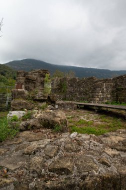Friuli Venezia Giulia (İtalya) bölgesindeki Meduno antik kalesinin kalıntılarında taş duvar. Yenileme aşamasında. Metal bir yapı iskelesi var, hava sisli..