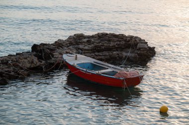 Kayalık kayalıkların yanında demirlemiş üç küçük teknenin yer aldığı romantik kıyı manzarası: ikisi demirli ve biri sudan kuru karaya çıkarıldı.