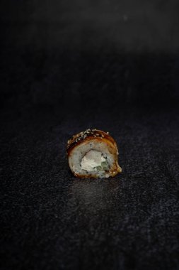 Siyah arka planda sushi, yılan balığı ve susamlı.