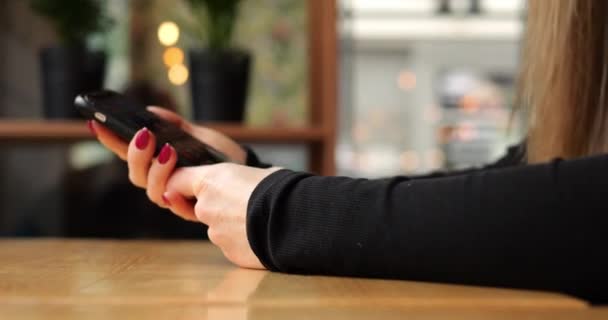 难以辨认的年轻女子把锁着的智能手机放在城市咖啡店的桌子上 拥有长发的匿名女性关掉手机 放在木制桌子上 高质量的4K镜头 — 图库视频影像