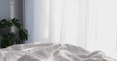 Güneşli bir günde beyaz pamuklu battaniye yatak odasında pencerenin önünde. Yeni günün başlangıcında hoş ve rahat bir bahar ya da yaz sabahı atmosferi. Yüksek kalite fotoğraf