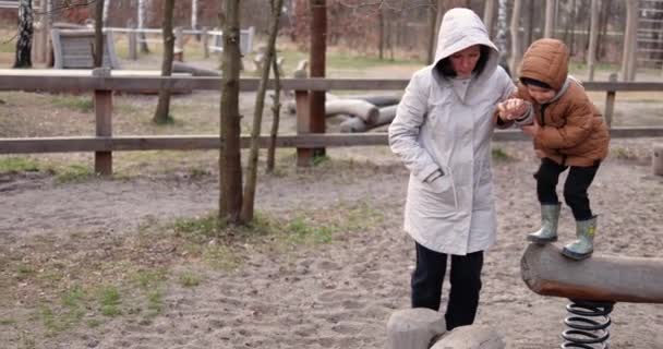 Mother Plays Son Wooden Playground Helping Jump Springy Beam Log — Stock Video