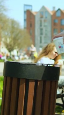 Dikey video tanınmayan bir kız ya da kadın tek kullanımlık kağıt bardağı sokağa atıyor. Anonim bir kadın şehrin yaya bölgesinde çöp tenekesi kullanıyor. Çevresel farkındalık kavramı.