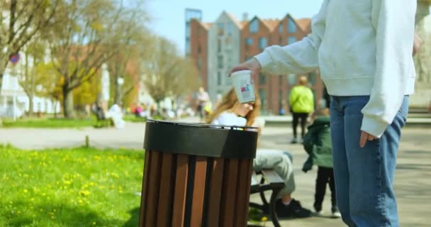 无法辨认的女孩或女人把一次性纸杯扔进街上的垃圾桶 无名女性使用安装在城市行人区外的垃圾箱 环境意识的概念 — 图库视频影像