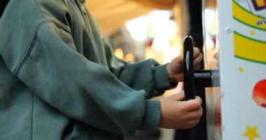 Küçük çocuk elleri video oyunu oynamak için direksiyonu çeviriyor. Tanımlanamayan ilkokul çocuğu bozuk para kullanan çocuklar sokak makinesiyle oynuyor..