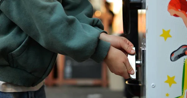 Çocuk ellerinin yakın çekimi kapsül oyuncak otomatının metal topuzunu döndürür. İsimsiz dört yaşındaki yeşil kazaklı çocuk Gashapon makinesinden gasha alıyor. Yüksek kalite fotoğraf