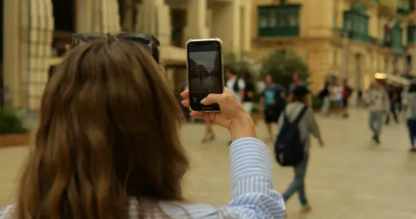 Tourist female student press shutter button in camera app on phone in street. View of smartphone screen while unrecognizable young woman takes photo in old downtown. High quality photo