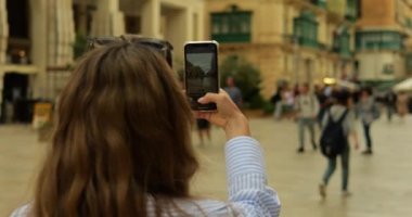 Turist kız öğrenci sokakta telefonda kamera uygulamasında düğmeye basıyor. Şehir merkezinde tanınmayan genç bir kadın fotoğraf çekerken akıllı telefon ekranının görüntüsü. Yüksek kalite 4k görüntü