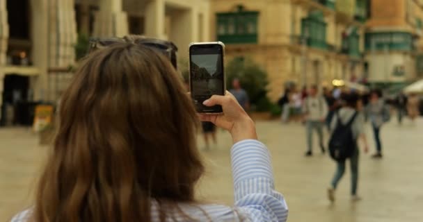 ストリートの携帯電話のカメラアプリの観光女性学生プレスシャッターボタン 認識できない若い女性がダウンタウンの古い写真を撮る間 スマートフォン画面のビュー 高品質の4K映像 — ストック動画