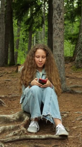 소녀는 미디어를보고 숲에서 스마트 폰에서 미디어를 사용합니다 인터넷과 디지털 중독의 — 비디오