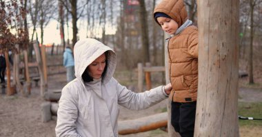 Anne, çocuk oyun parkında tahta direkten geçerken beş yaşındaki çocuğu emniyete alıyor. Küçük oğlu güler ve soğuk bir sonbahar gününde ailesiyle dışarıda vakit geçirmekten hoşlanır..