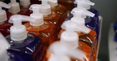 Etiketlenmemiş kırmızı, mavi, turuncu renkli plastik şişelerin yakın çekimi. Perakende indirim mağazasındaki karton kutuda genel çok renkli sıvı kozmetik ve vücut bakımı ürünleri.